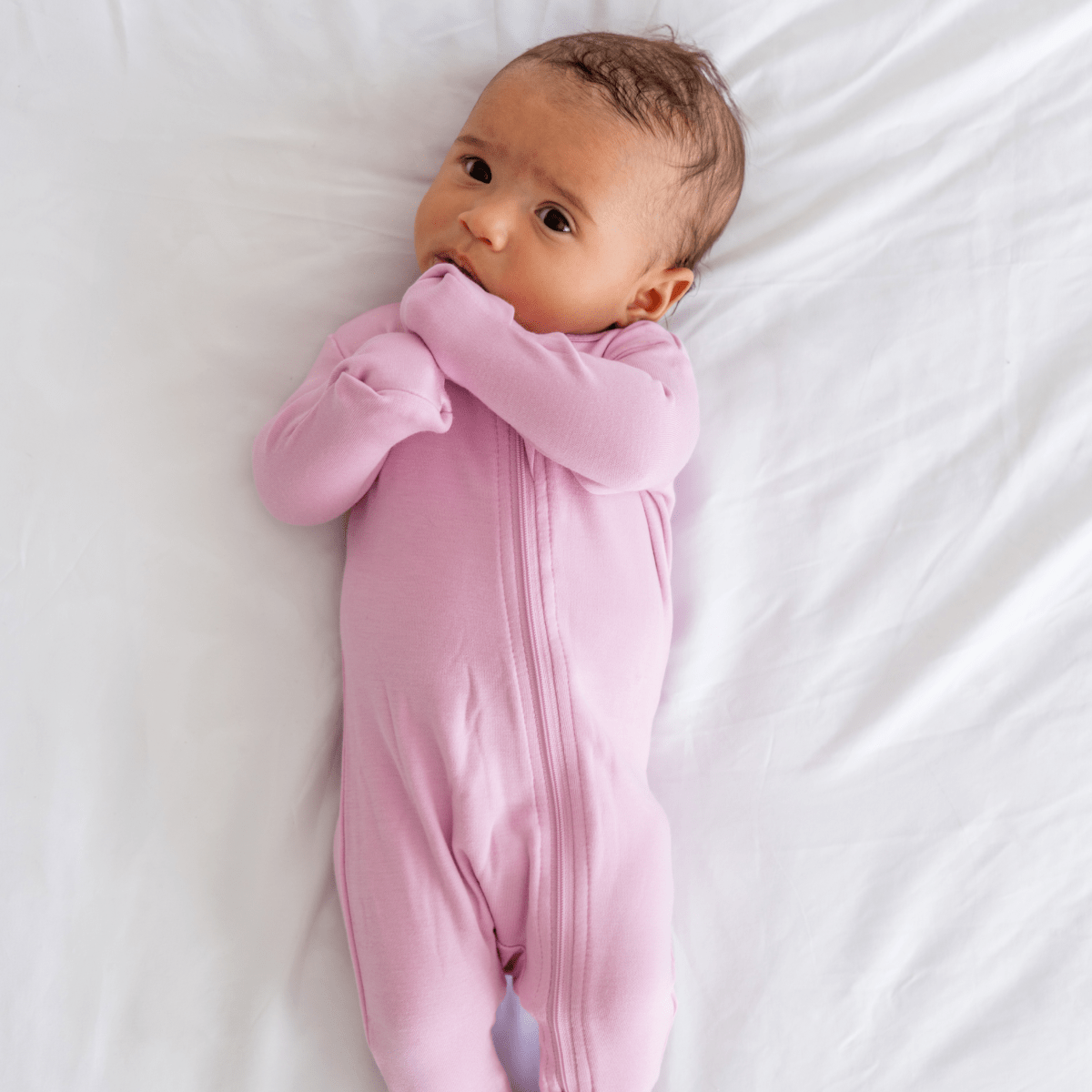Baby in soft bamboo pajamas with DreamCuffs® from Dreamland Baby, featuring cozy fabric and secure, stretchy cuffs.