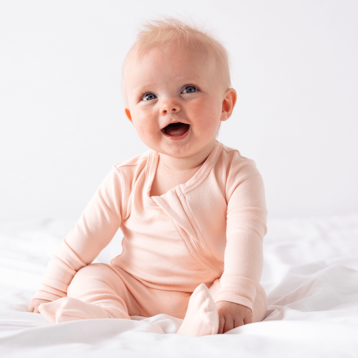 Baby in soft bamboo pajamas with DreamCuffs® by Dreamland Baby, showing cozy sleepwear with adjustable cuffs.