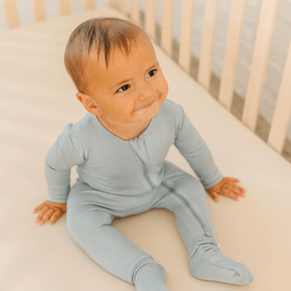 Baby in soft bamboo pajamas with DreamCuffs® from Dreamland Baby, featuring footed design and cozy cuffs for comfort.