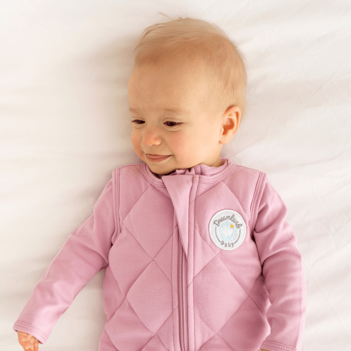Dreamland Baby weighted sleep sack lying open, showing soft fabric and adjustable straps, designed for comfortable sleep.