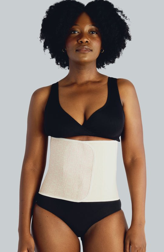 A woman wearing the Original Belly Bandit by Aimee Nursing Gowns, showcasing the supportive postpartum belly band.