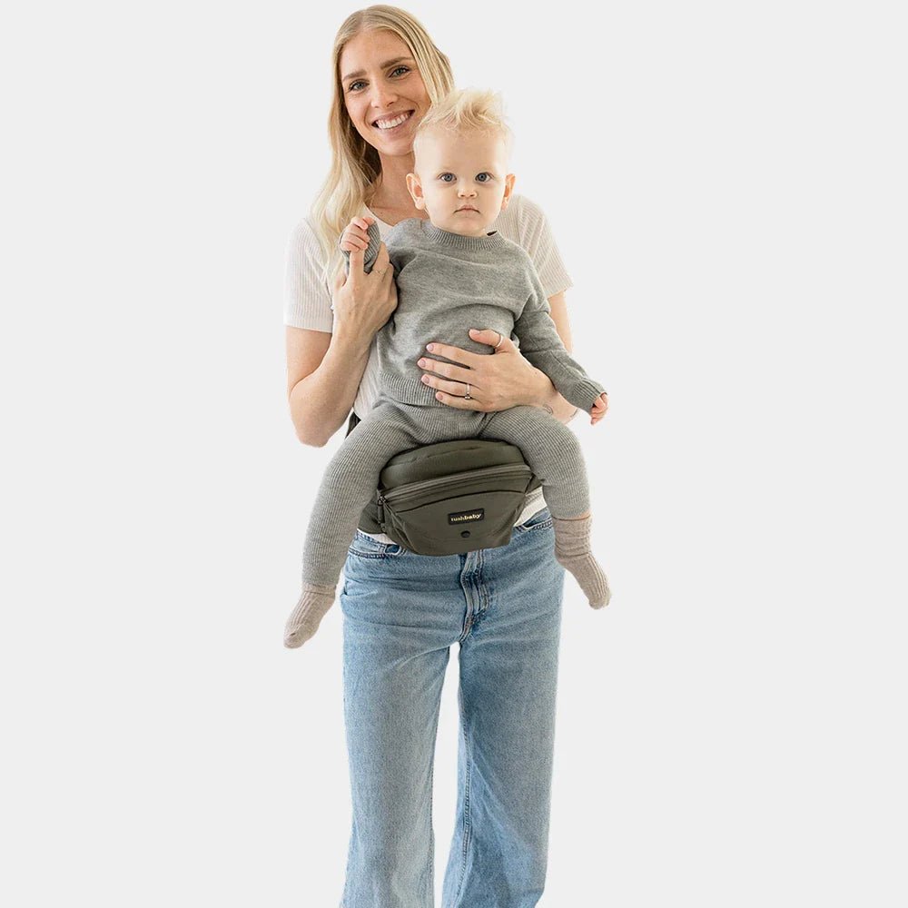 Baby wearing the Tushbaby Hip Carrier, a comfortable toddler carrier with supportive waist belt and adjustable straps for easy carrying.