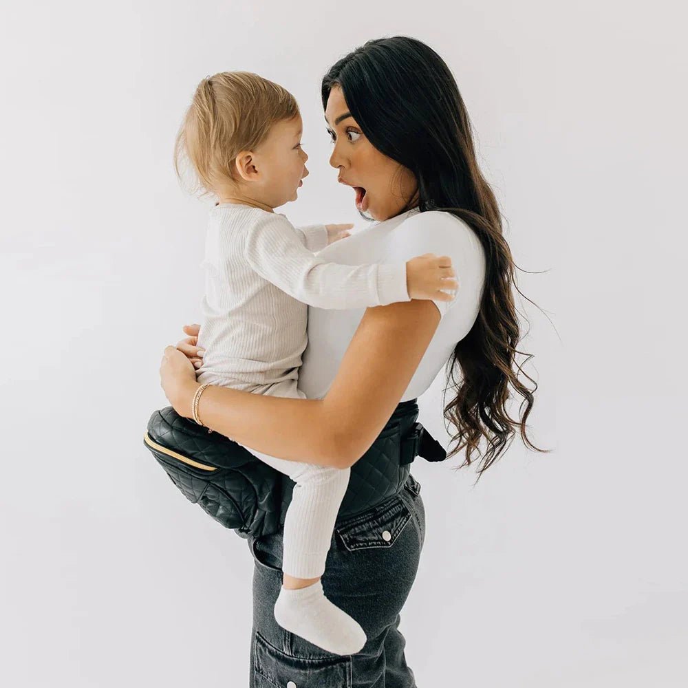 Tushbaby Hip Carrier for babies and toddlers, black fabric with adjustable straps and ergonomic design for comfortable carrying.
