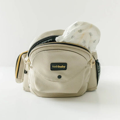 Tushbaby Hip Carrier for babies and toddlers showing the adjustable strap and ergonomic design in a natural setting.