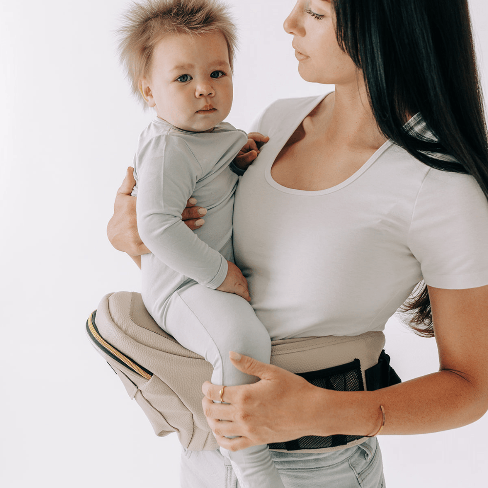 Baby wearing Tushbaby hip carrier with adjustable straps and supportive design for comfortable toddler carrying.