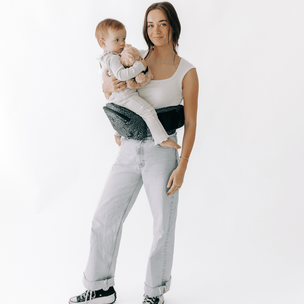 Baby being carried in Tushbaby hip carrier, a toddler carrier designed for comfortable baby and toddler support.