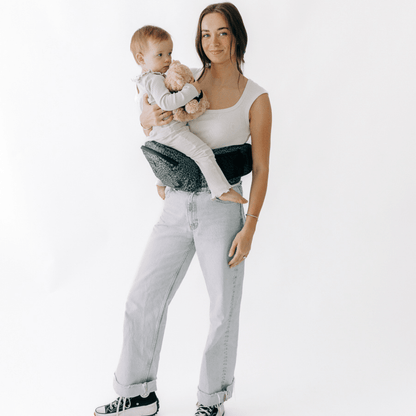 Baby being carried in Tushbaby hip carrier, a toddler carrier designed for comfortable baby and toddler support.