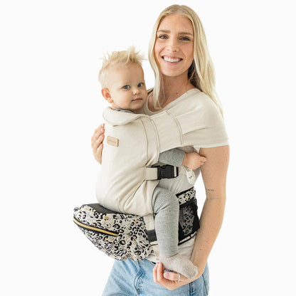 Baby wearing the Tushbaby Hip Carrier, a soft, ergonomic baby and toddler carrier in neutral colors, designed for comfortable carrying.