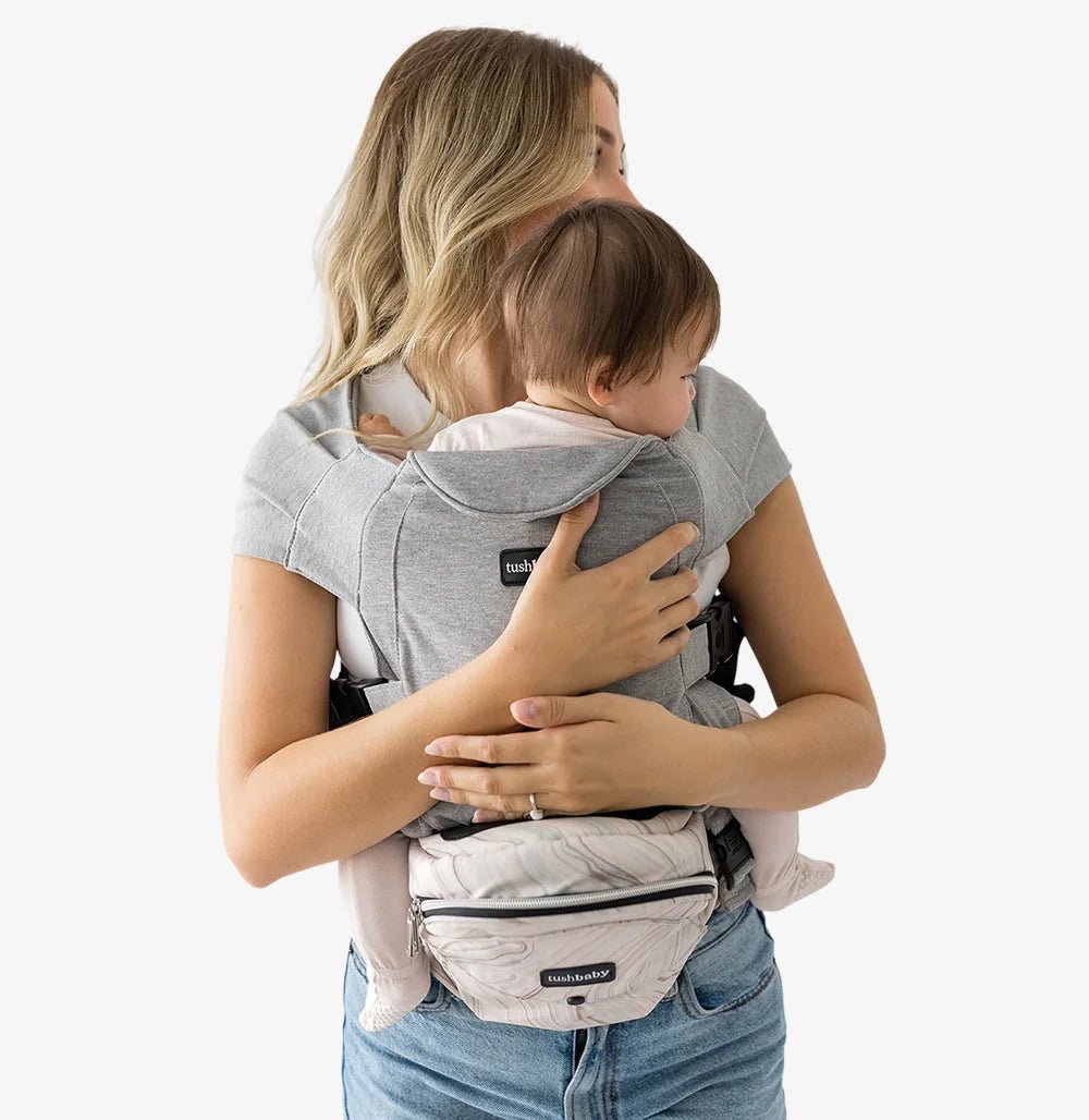 Tushbaby hip carrier for babies and toddlers, featuring adjustable straps and ergonomic design in a neutral color.