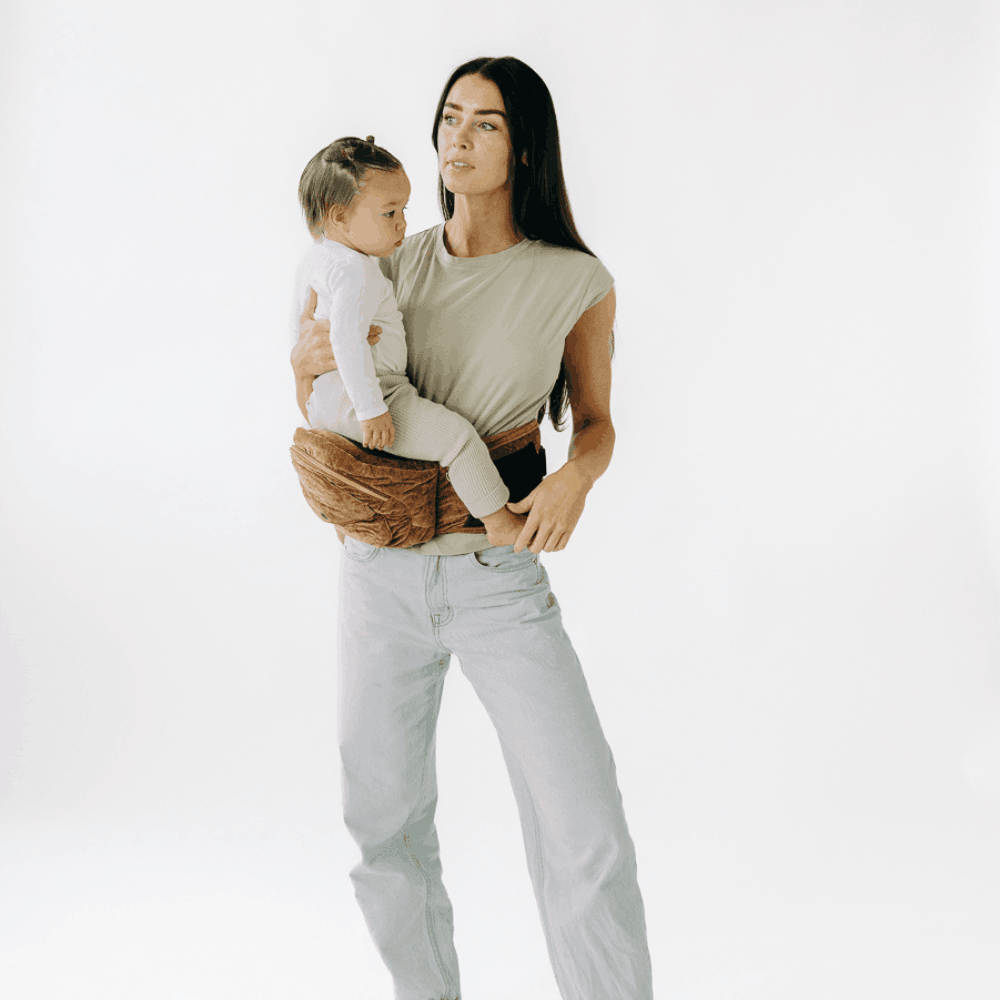 Tushbaby Hip Carrier for baby and toddler, featuring adjustable straps and padded support in a neutral color.