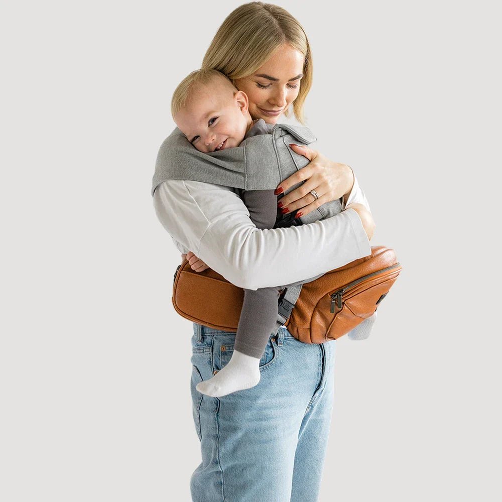 Tushbaby Hip Carrier for babies and toddlers, soft fabric with adjustable straps, designed for comfortable parent and child wear.