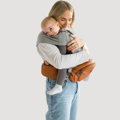 Tushbaby Hip Carrier for babies and toddlers, soft fabric with adjustable straps, designed for comfortable parent and child wear.