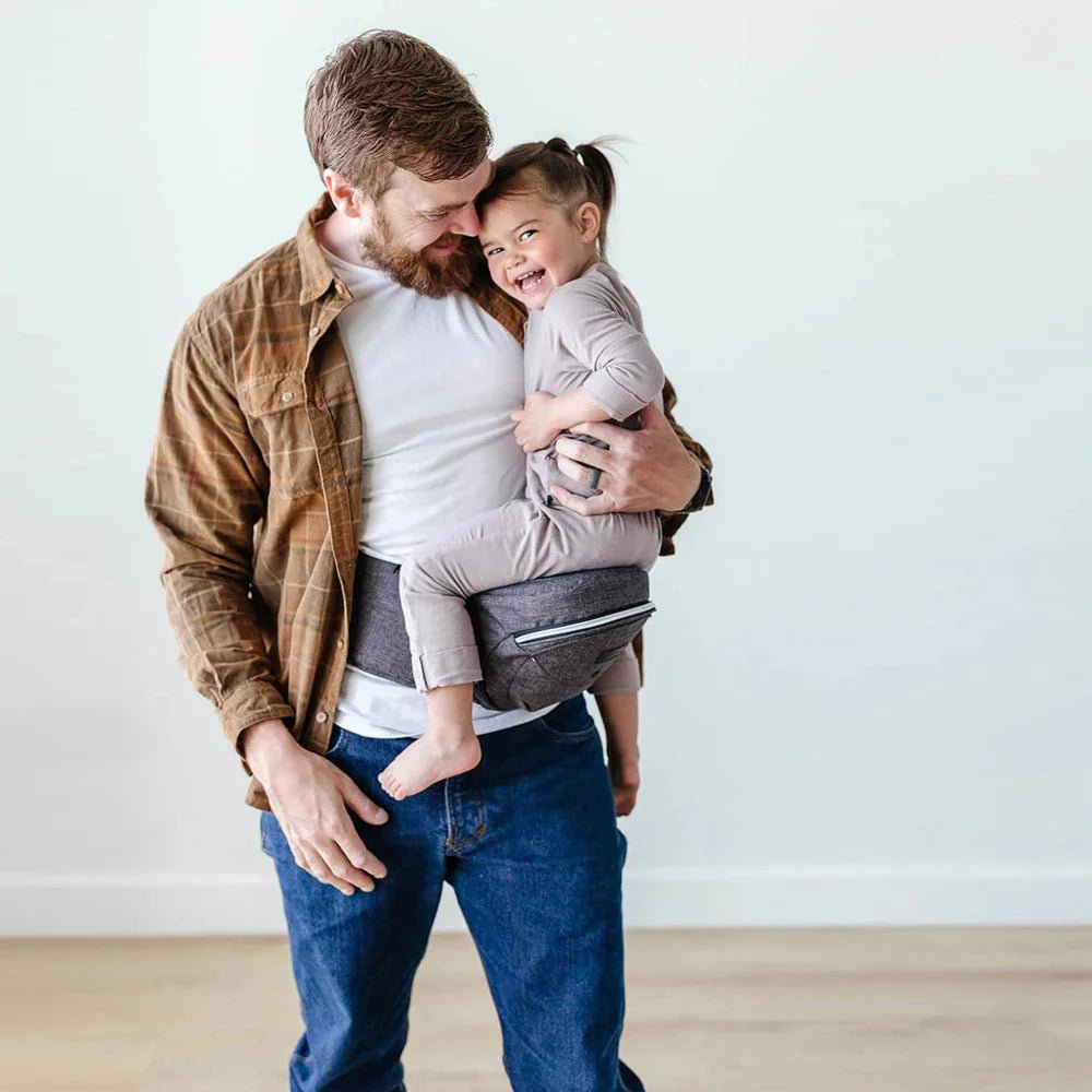Tushbaby Hip Carrier for babies and toddlers, shown in beige with adjustable straps and ergonomic design for comfortable carrying.