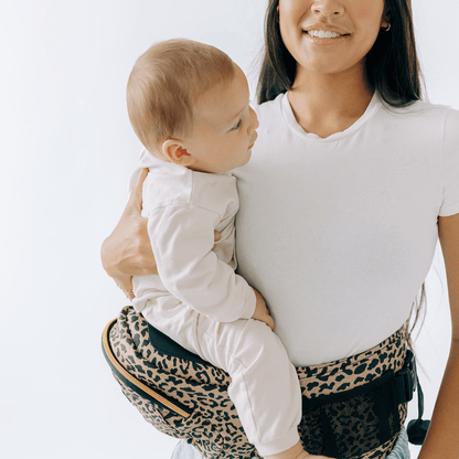 Baby wearing the Tushbaby Hip Carrier, a comfortable and supportive baby and toddler carrier in a neutral fabric.