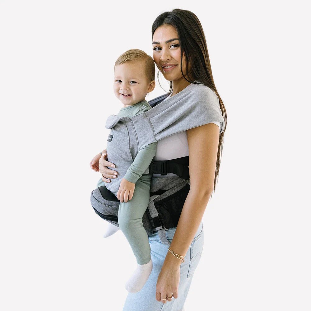 Tushbaby Hip Carrier for baby and toddler, showing ergonomic design and adjustable straps in a natural setting.