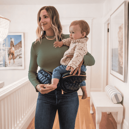 Tushbaby Hip Carrier for babies and toddlers, black fabric with padded seat and adjustable straps for comfortable carrying.