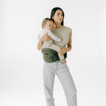 Baby wearing the Tushbaby Hip Carrier in a toddler, showing the supportive waistband and ergonomic design for comfortable carrying.