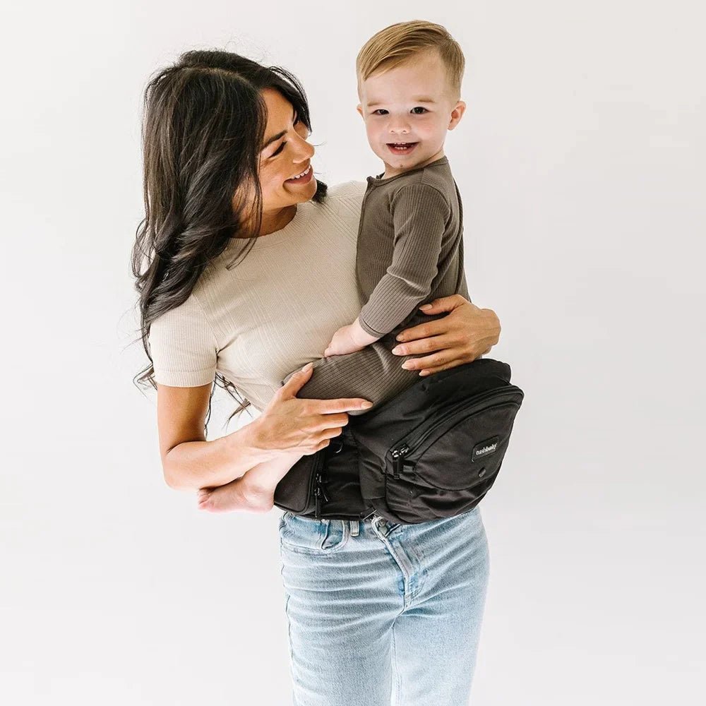 Tushbaby Hip Carrier for babies and toddlers, black fabric with adjustable straps and ergonomic design for comfortable carrying.
