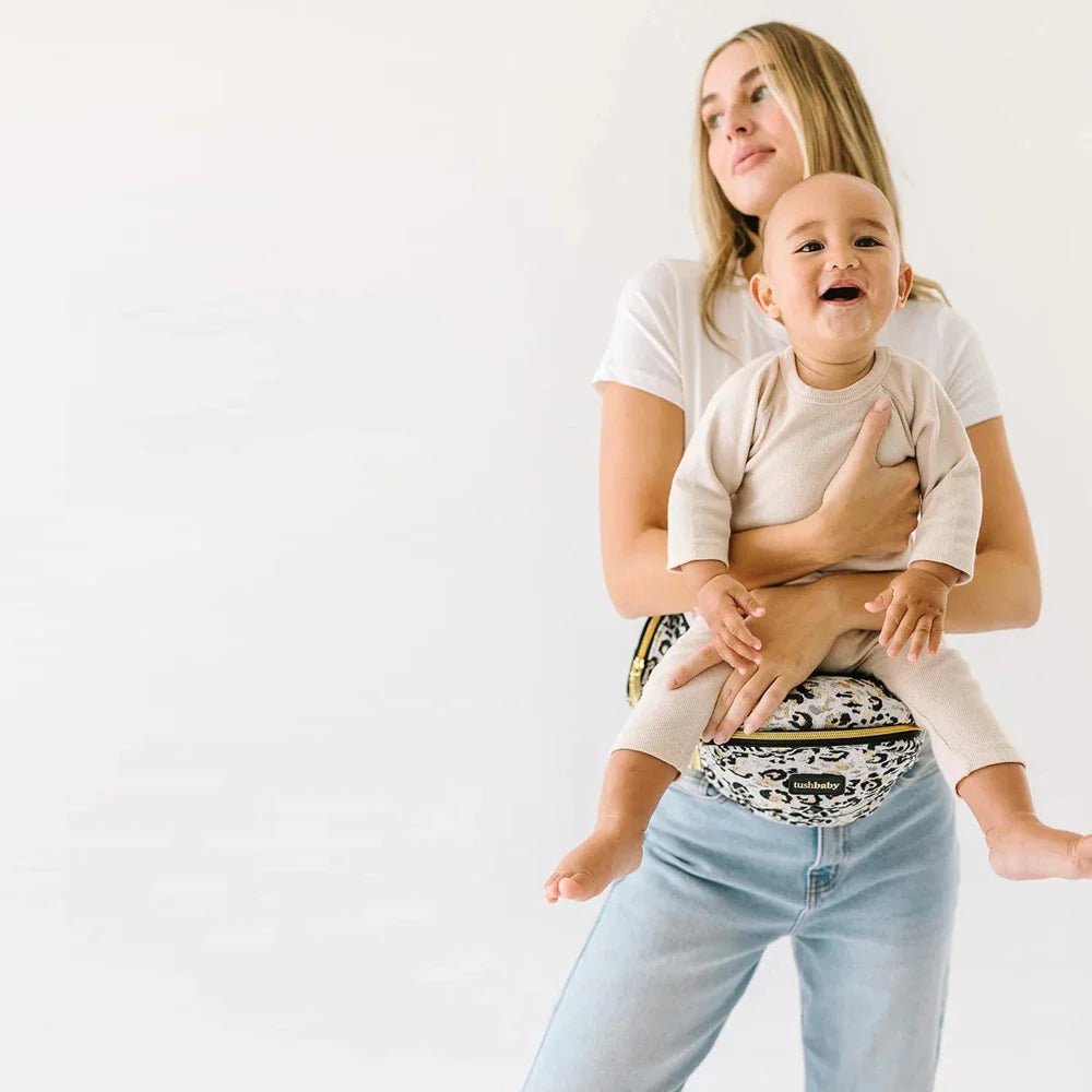 Tushbaby Hip Carrier for babies and toddlers, black fabric with ergonomic design, adjustable straps and padded support.