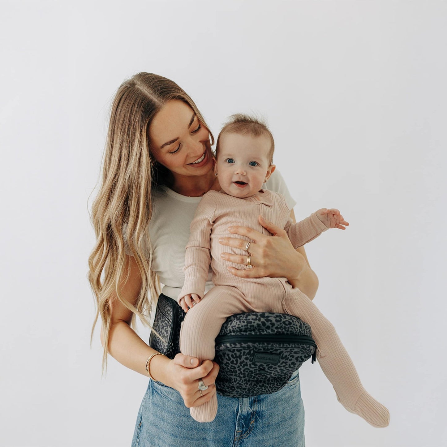 Tushbaby Hip Carrier for babies and toddlers, gray fabric with adjustable straps and ergonomic design for comfortable carrying.