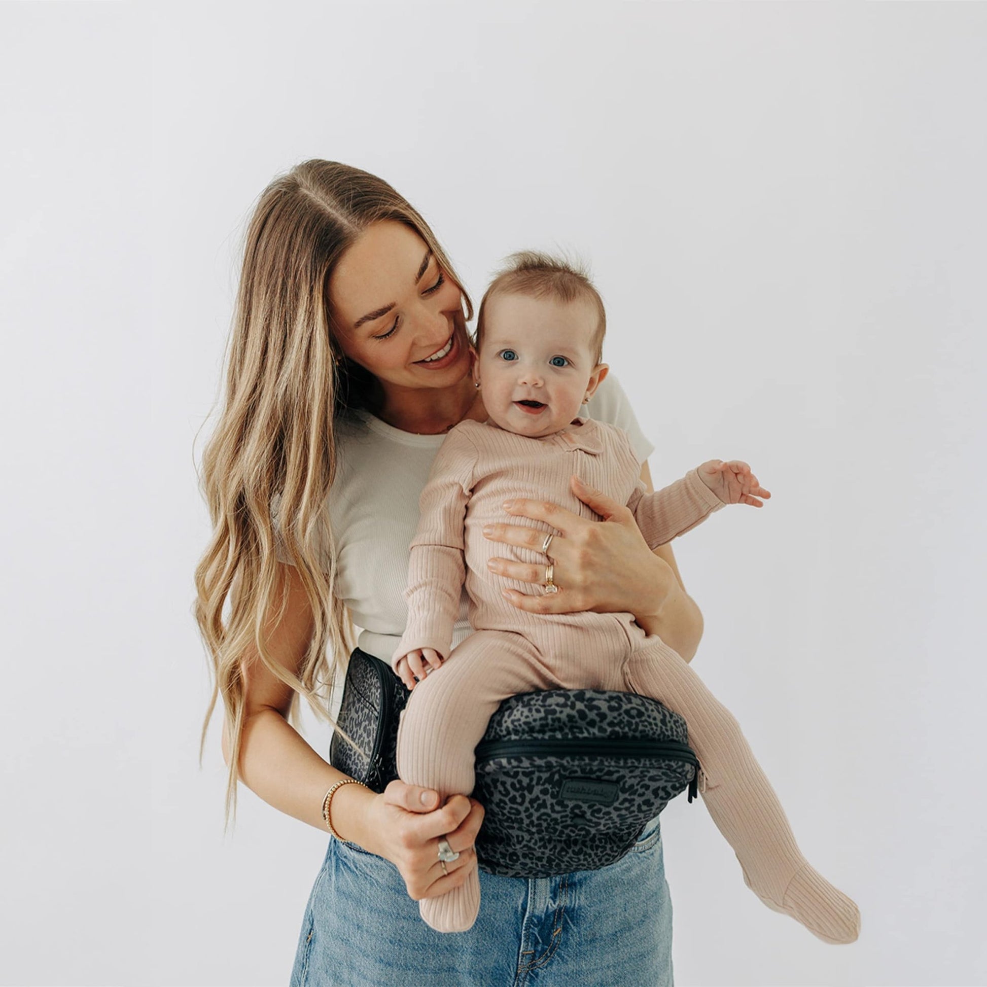 Tushbaby Hip Carrier for babies and toddlers, gray fabric with adjustable straps and ergonomic design for comfortable carrying.