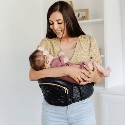 Tushbaby Hip Carrier for babies and toddlers, black fabric with adjustable straps and ergonomic design for comfortable carrying.