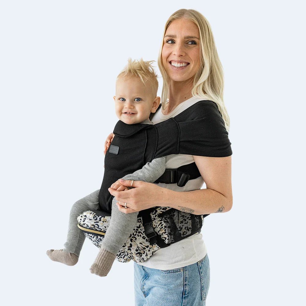 Tushbaby Hip Carrier for babies and toddlers, black fabric with adjustable straps, designed for comfortable parent and child bonding.
