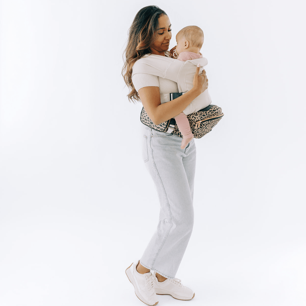 Tushbaby Hip Carrier for babies and toddlers, showing adjustable straps and ergonomic design in a neutral color.