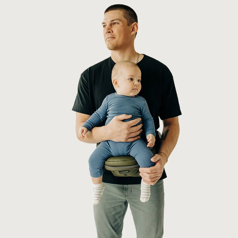 Baby being carried in Tushbaby hip carrier, a comfortable and ergonomic baby and toddler hip carrier by Tushbaby.