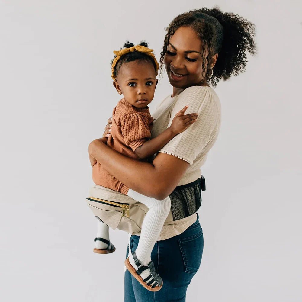 Tushbaby Hip Carrier for baby and toddler, shown in a neutral color, worn around the waist for comfortable parenting support.
